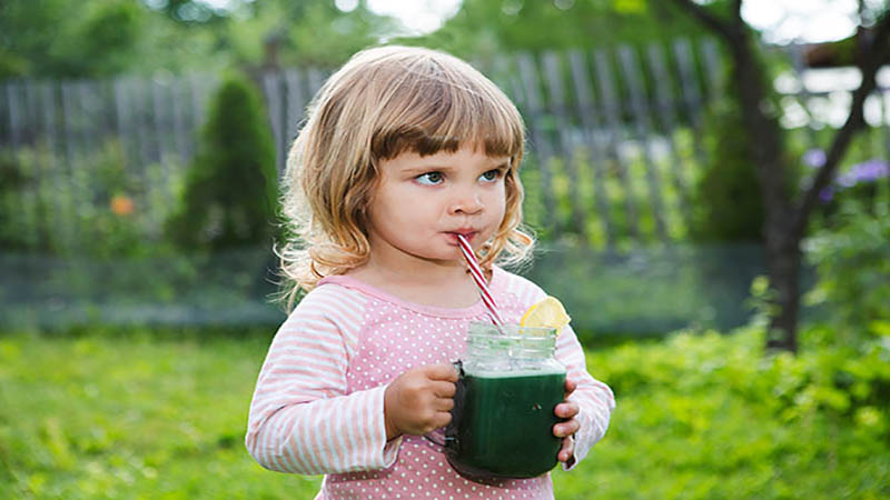 Enfant fille boit un smoothie à la spiruline